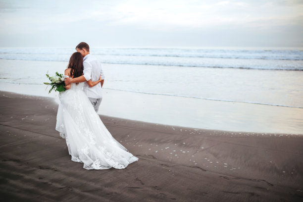 优雅华丽的新娘和新郎走在海边的日落时间。图片下载