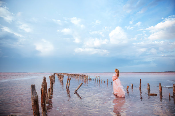 年轻孕妇在粉色湖面上享受阳光图片下载