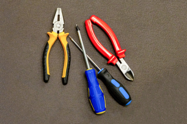 螺丝起子、钳子、手工工具固定修补背景纹理、施工设计在深色基材上图片下载