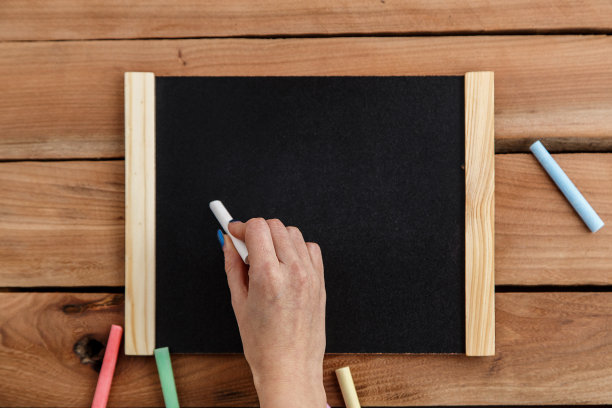 女人手在木制背景的木制黑板上写字，顶视图图片下载