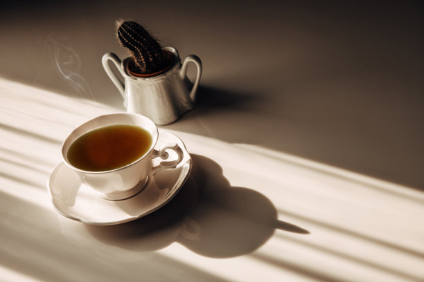 桌上的热茶杯和透过窗户的光线在早上好茶或有一个美好的一天。茶时间或咖啡休息放松田园的概念。图片下载