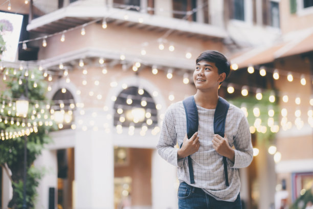 背着背包独自走过城市街道的男子旅行者。图片下载