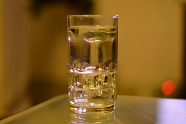 玻璃杯放在玻璃桌面上，上面放着水。图片下载