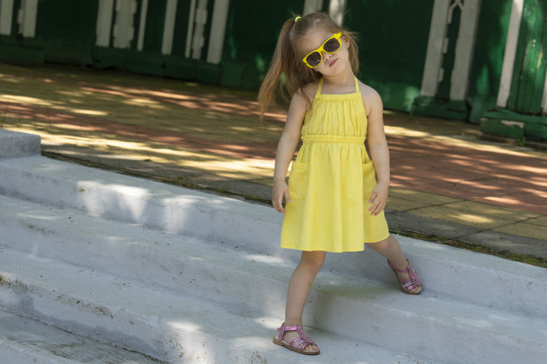 小孩模特穿着黄色的裙子。一名女孩为时尚的儿童用品做广告，参与拍摄照片。图片下载