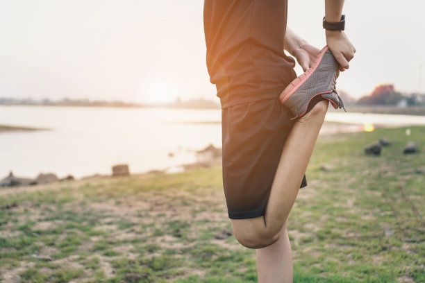 迷人的运动员女孩在公园里伸展，在日落前跑步集中在鞋子上。运动的概念。体育生活方式图片下载