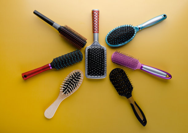 各种颜色的刷子和梳子，用于黄色背景的头发。图片下载