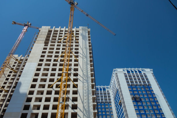 白色在建的高层建筑和塔吊映衬着蓝天。图片下载