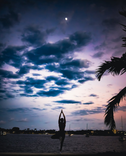 女人在黄昏练习瑜伽在海滨美丽的fit和健康图片下载