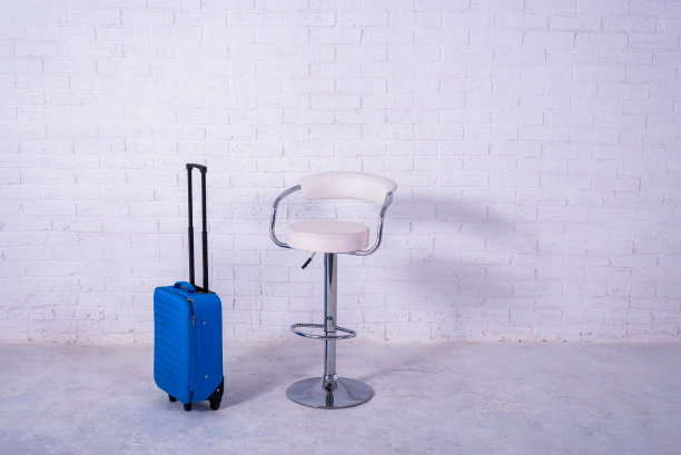 白色砖墙旁的蓝色行李箱和高脚椅。空间的文本图片下载