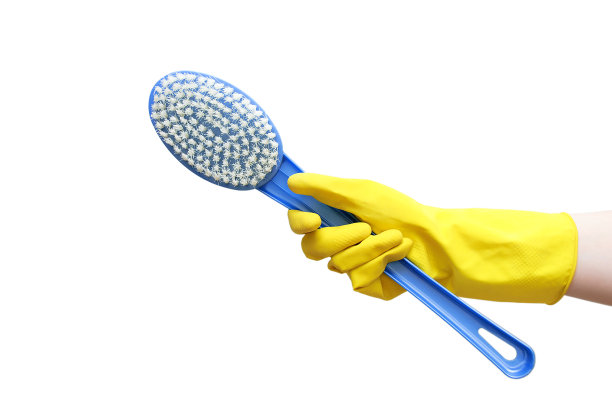 一只戴着黄色橡胶手套的手拿着蓝色的刷子进行清洁。白色的隔离。特写镜头。图片下载