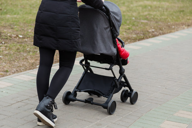 女孩推着婴儿车在公园里散步图片下载