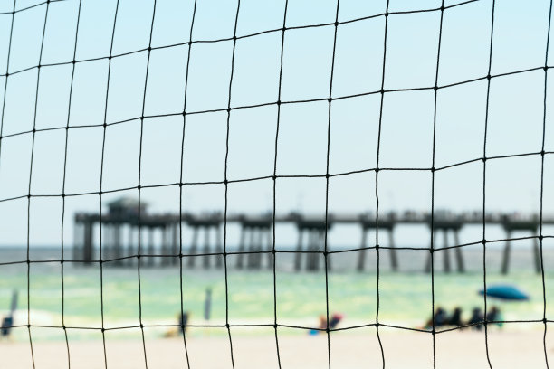 沃尔顿堡海滩，奥卡卢萨岛捕鱼码头在佛罗里达州，墨西哥潘汉德尔湾的夏天与近距离观看沙滩排球网人在模糊的背景图片下载