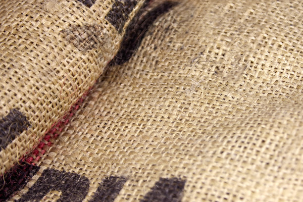 近距离图片折叠皱巴巴的空旧粗麻布与大印刷字母。生态、自然的面料包装问题，质朴的背景。图片下载