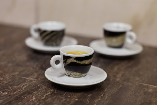 近距离图片的三个小杯子和茶碟，咖啡浓缩，与老虎图案设计，在大理石的背景。图片下载