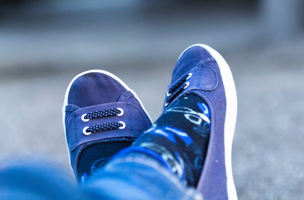 个人观点的年轻女子的腿交叉在脚踝上穿着可爱的蓝色帆布鞋图片下载