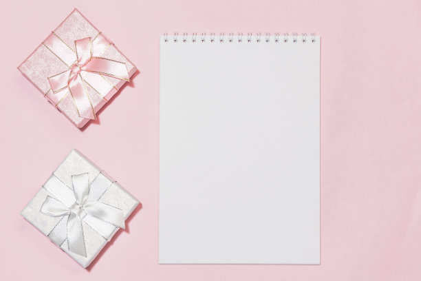 节日背景与礼物包装与粉红色，银色，颜色与一个柔和的颜色蝴蝶结在一个精致的粉红色背景笔记本书写文本与模型与复制空间图片下载