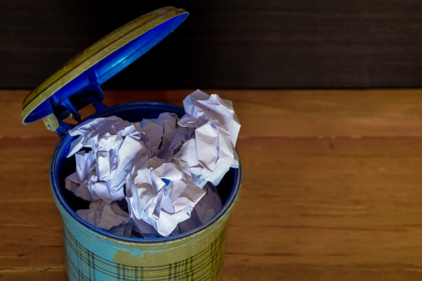 地板上垃圾桶里的皱巴巴的纸进进出出。图片下载