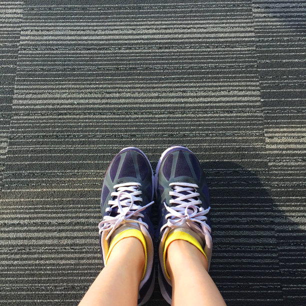 女性在紫色运动鞋鞋孤立。前视图。女人穿跑步运动鞋城市地毯背景。图片下载