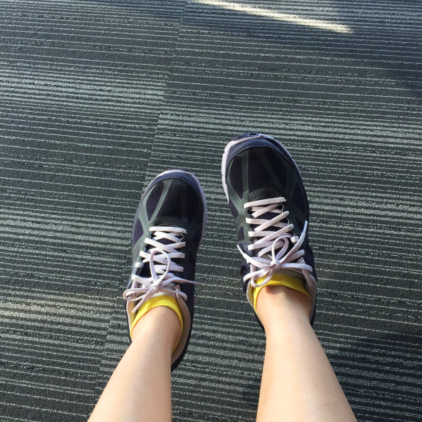 女性在紫色运动鞋鞋孤立。前视图。女人穿跑步运动鞋城市地毯背景。图片下载