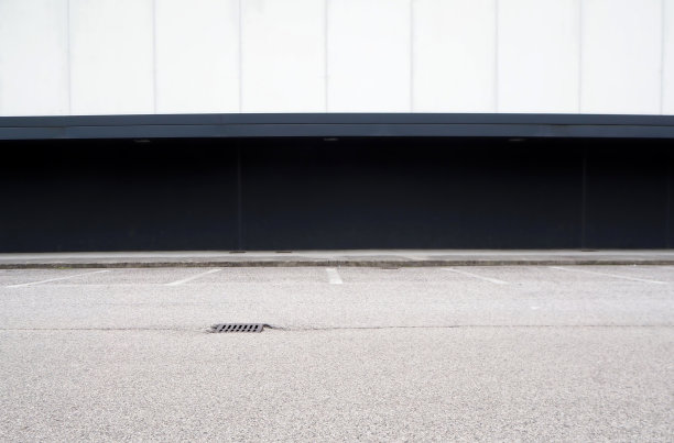 黑白相间的现代建筑，前面有人行道和柏油路。城市背景的复制空间图片下载