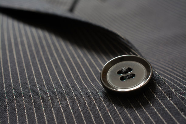 西装纽扣的特写细节在别针剥离的布料上。定制的背景图片下载