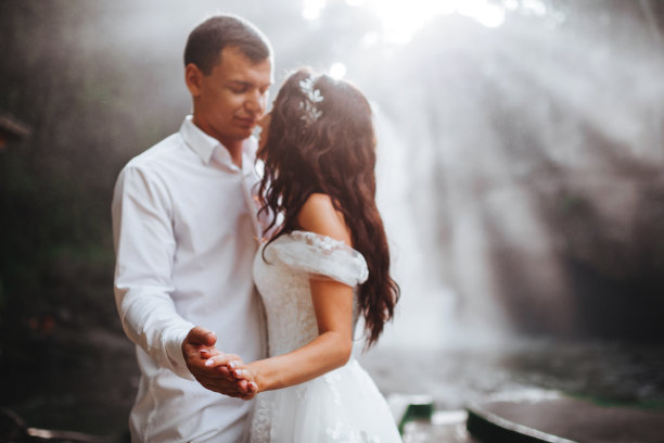 年轻的情侣在相爱的新郎和新娘，婚礼的日子附近的山上瀑布。图片下载