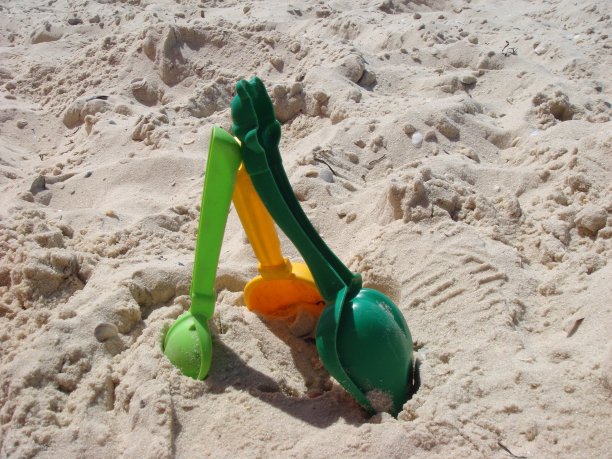 一套彩色塑料儿童玩具在沙滩附近的海。图片下载