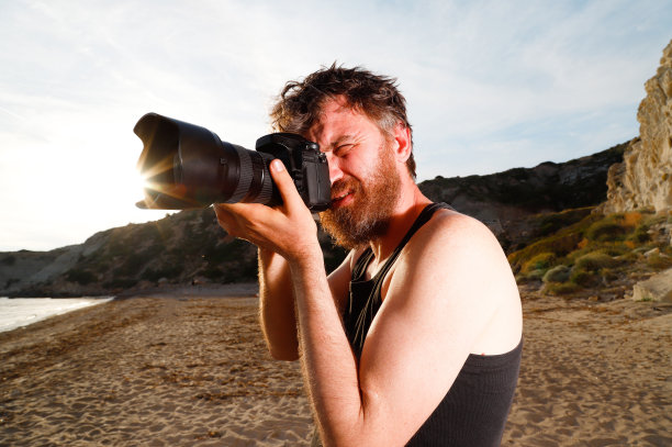 男子在海滩上用专业相机拍照图片下载
