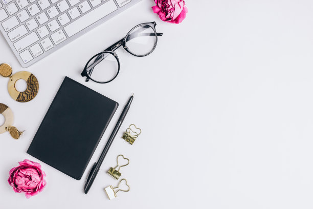 有电脑键盘、笔记本、钢笔、眼镜和鲜花的女性工作场所图片下载