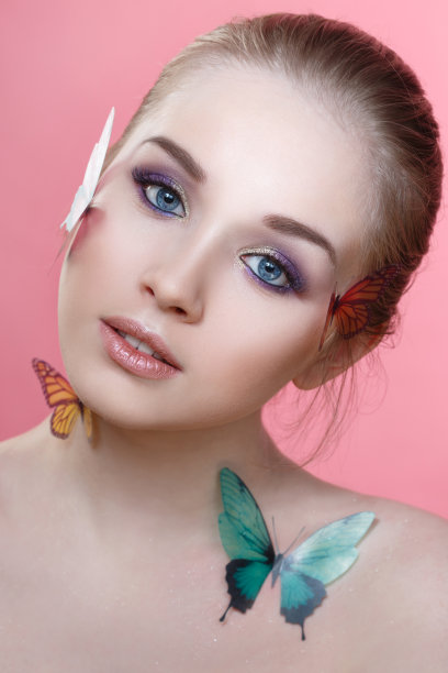 美丽时尚的肖像美丽的女孩与温和的化妆和蝴蝶在她的脸孤立在粉红色的背景。图片下载