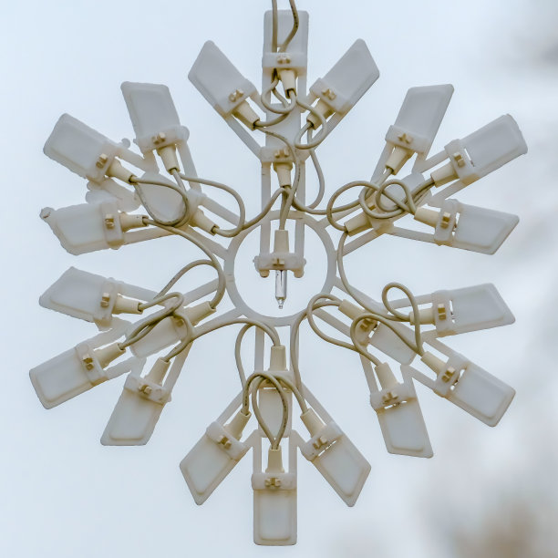 一个白色雪花的圣诞装饰对模糊的天空和树的特写图片下载