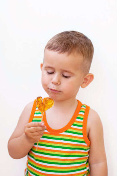 漂亮的两岁男孩看着棒棒糖图片下载