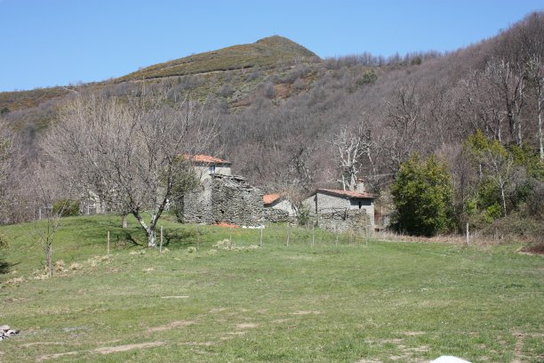 在托斯卡纳亚平宁地区的阿普利亚阿尔卑斯山脉上一大片绿色空地上被遗弃的小房子图片下载