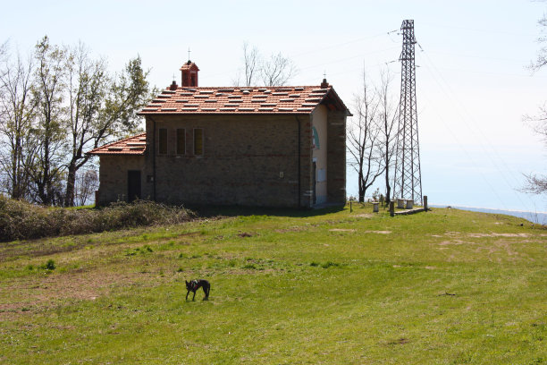 一个阳光明媚的春日，在托斯卡纳亚平宁山脉的阿波安阿尔卑斯山的一片空地上被遗弃、废弃的小教堂图片下载