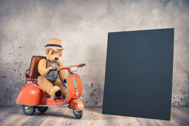 复古的泰迪熊玩具在草帽上坐在老儿童从60年代脚踏摩托车，皮革背包和空黑色黑板空白。学校男孩或儿童旅行者的概念。复古风格滤镜照片图片下载