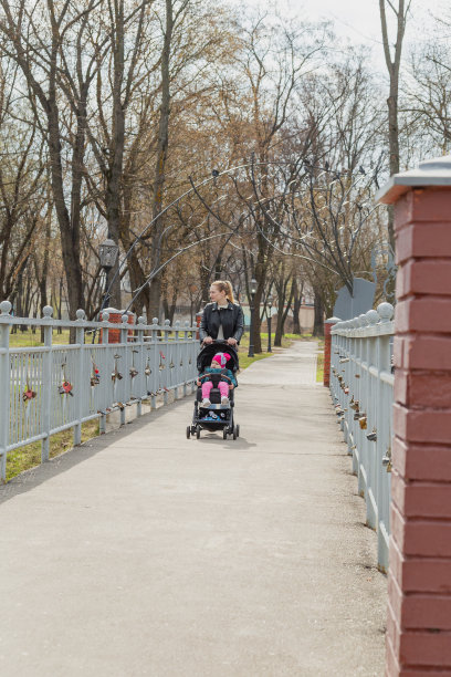 年轻的母亲推着婴儿车走着图片下载