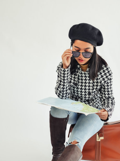 亚洲女游客穿着冬季夹克，坐在复古的棕色包里，冬天，看着她手里的地图，生活方式的概念。图片下载