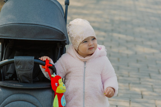 一个小女孩在公园里推着婴儿车。孩子在公园里玩婴儿车图片下载