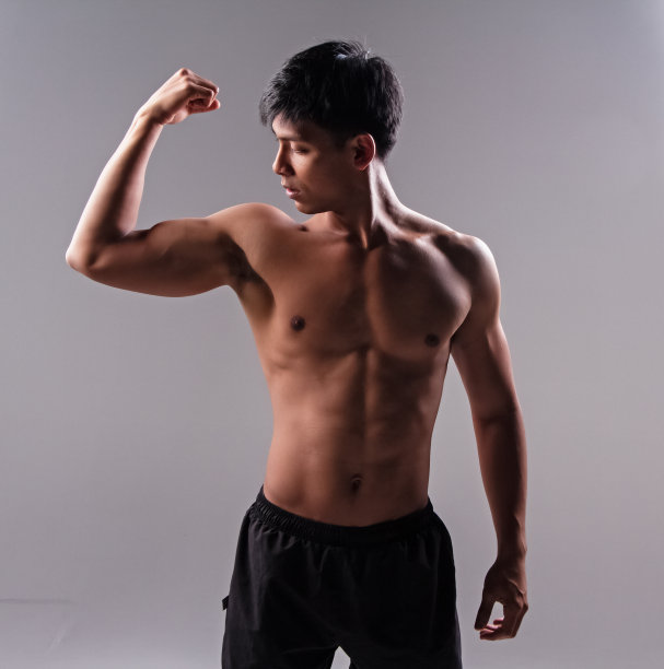 帅哥秀身体肌肉，举手秀强壮手臂，身体健康源于运动，灯光模糊周围图片下载