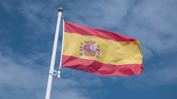 西班牙国旗在晴朗的蓝天中飘扬。图片下载