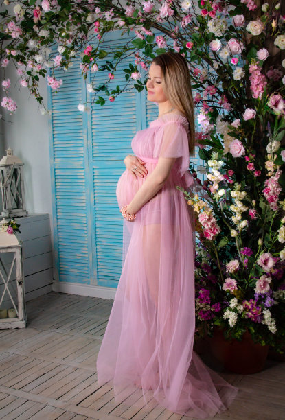 美丽的孕妇穿着粉红色的裙子在拱形的鲜花图片下载