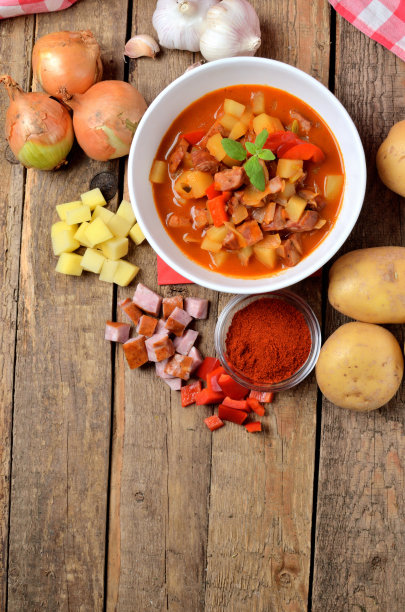 从上面俯瞰木桌上的土豆、香肠炖牛肉、胡椒、洋葱和大蒜的垂直照片图片下载