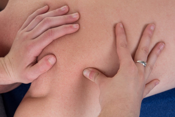 女性治疗师用拇指在男性背部做治疗性按摩的特写图片下载