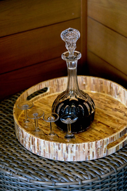 玻璃或水晶瓶液体和玻璃杯在木制的圆形托盘在桌子上图片下载