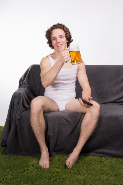 一个喝着啤酒的帅哥在看电视。图片下载