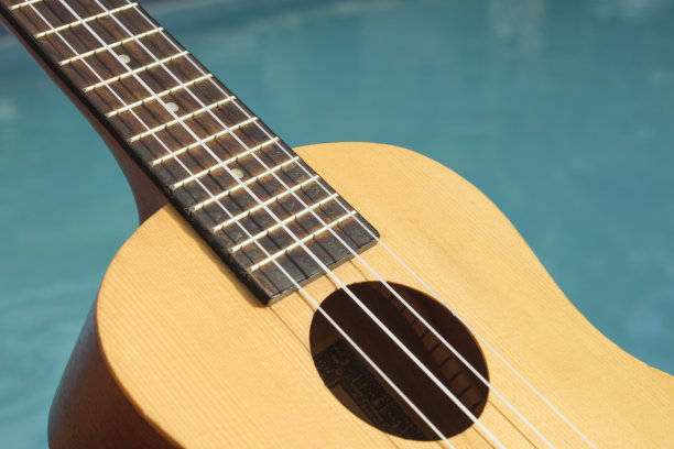 尤克里里琴的细节与游泳池的背景图片下载