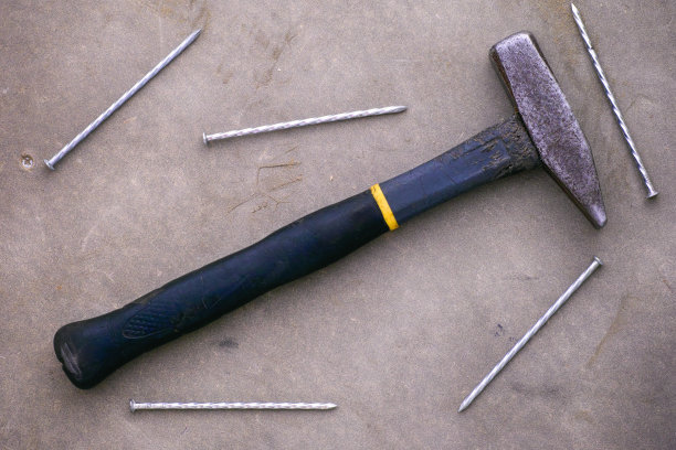 手里拿着锤子和钉子。灰色的背景。图片下载