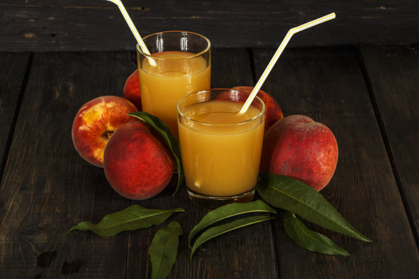 桃子鲜榨汁与新鲜桃子在一个黑暗的背景。俯视图，复制空间。健康饮食。鲜榨桃子汁。新鲜桃子是健康食品。图片下载