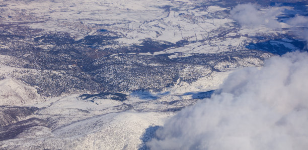 雪山的背景和白云在他们之上。从飞机窗户拍摄的航拍照片。图片下载