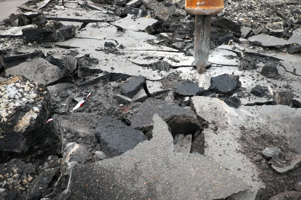 在修路工程中，挖掘机用液压锤钻压碎混凝土路面。道路检修，维修地点图片下载